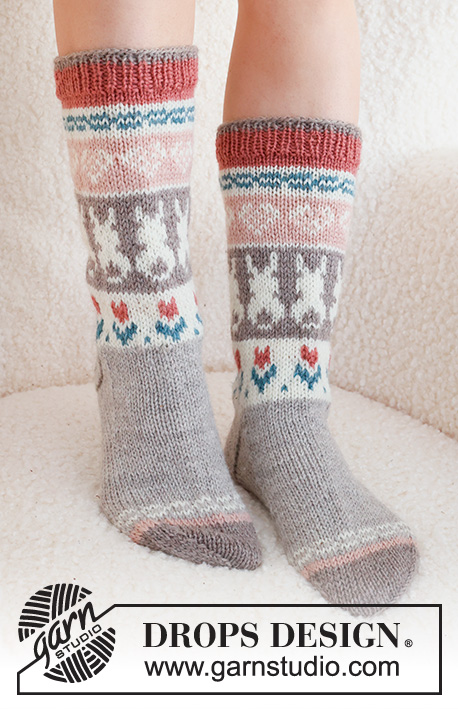 Dancing Bunny Socks / DROPS 229-34 - Gebreide sokken in DROPS Karisma. Het werk wordt van boven naar beneden gebreid in tricotsteek met veelkleurig patroon en hart, Paashaas en bloem. Maten 35 - 46. Thema: Pasen.